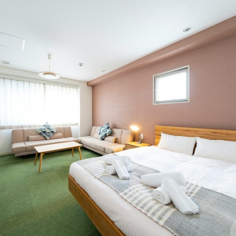 Helles, modernes Hotelzimmer mit Doppelbett, Couch und Sitzbereich.